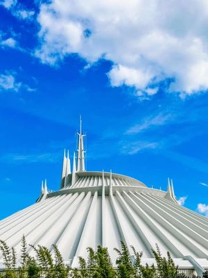 Space Mountain's iconic white dome rises against a bright blue sky at Walt Disney World's Magic Kingdom theme park.