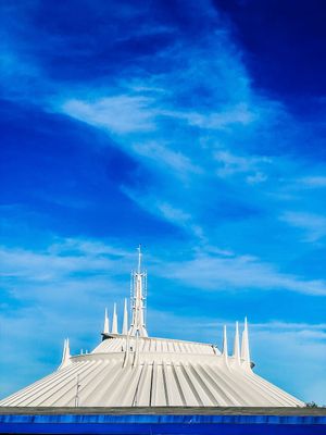 Space Mountain's iconic white spires and dome rise against a vibrant blue sky at Disney World's Magic Kingdom.