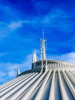 Space Mountain's iconic white spires and ridged dome architecture against vivid blue sky at Disney World's Magic Kingdom.