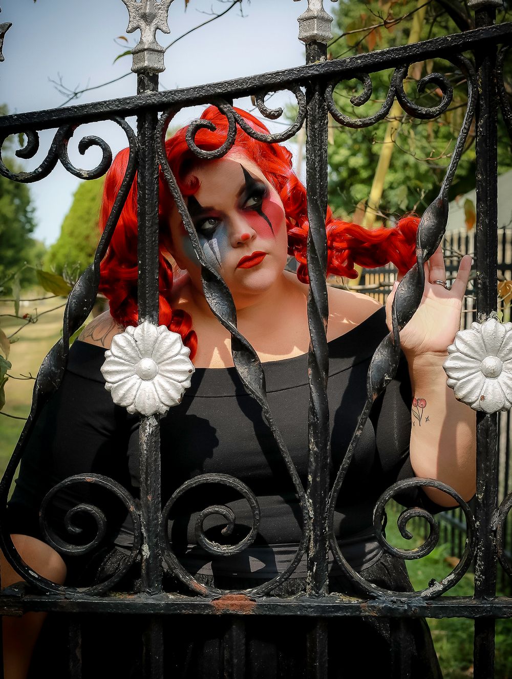 Gothic portrait at ornate iron gate with vintage-inspired styling and dramatic makeup.