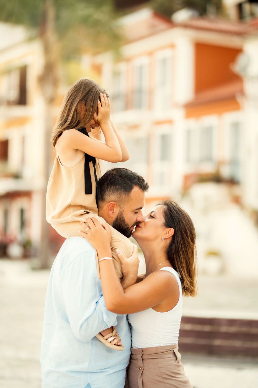 Intimate family moment captured against warm-toned Mediterranean architecture.