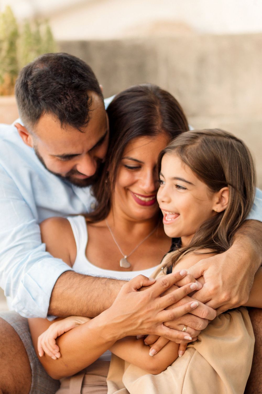 Intimate family moment shared in warm embrace against neutral background.