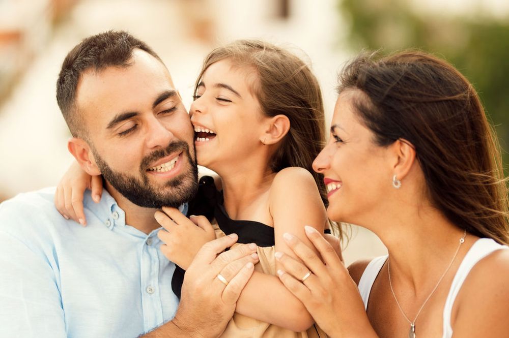 Close-up of three people sharing an intimate moment of laughter outdoors.