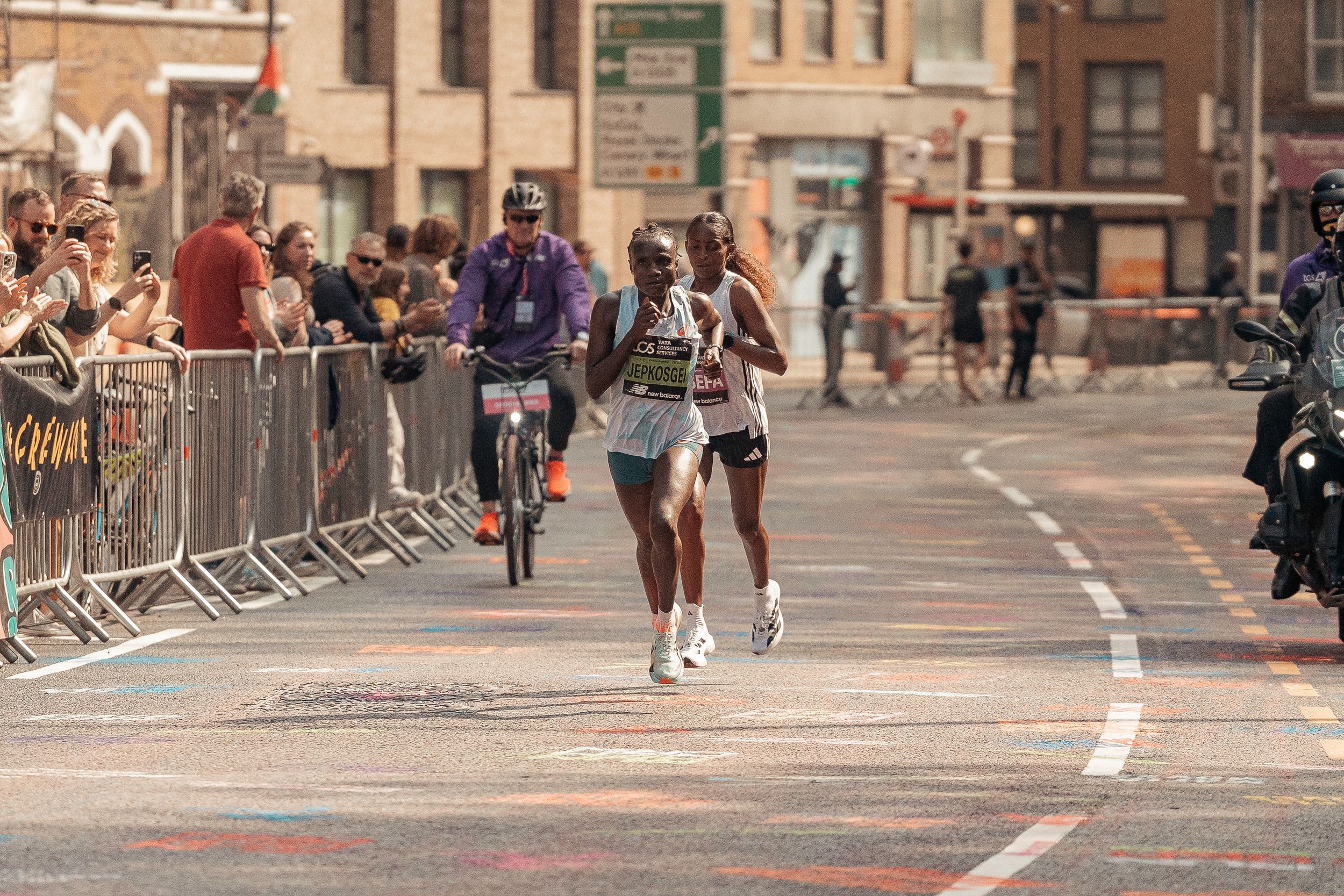 Tigist Assefa competes while spectators cheer from behind barriers during the 2025 London Marathon.