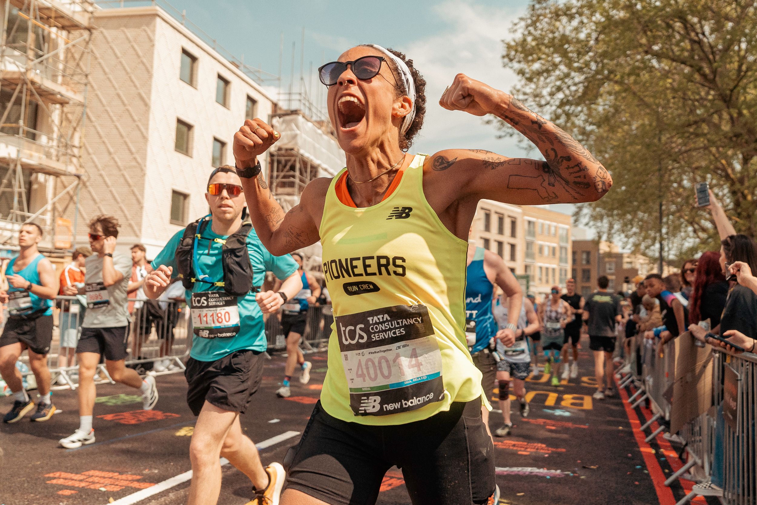 Marathoner from Pioneers celebrates with intense joy while racing through city streets surrounded by other participants and spectators.
