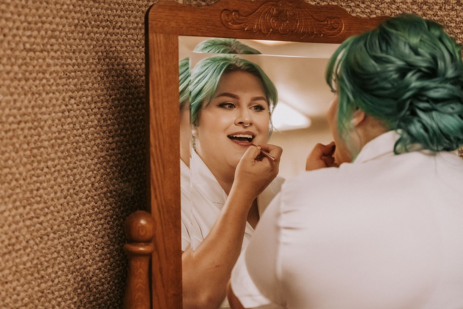 A bride applies lipstick while looking in a mirror. Small wedding in New Mexico. Intimate wedding venues. Albuquerque Garden Center weddings