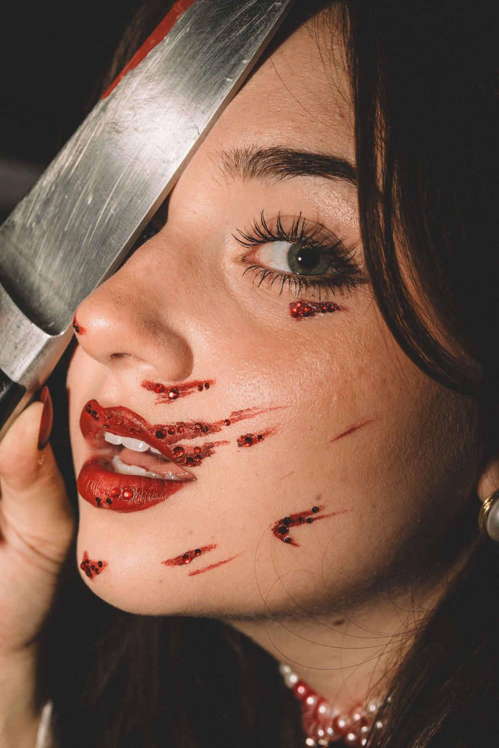 Closeup of Halloween makeup featuring fake blood effects and knife prop.