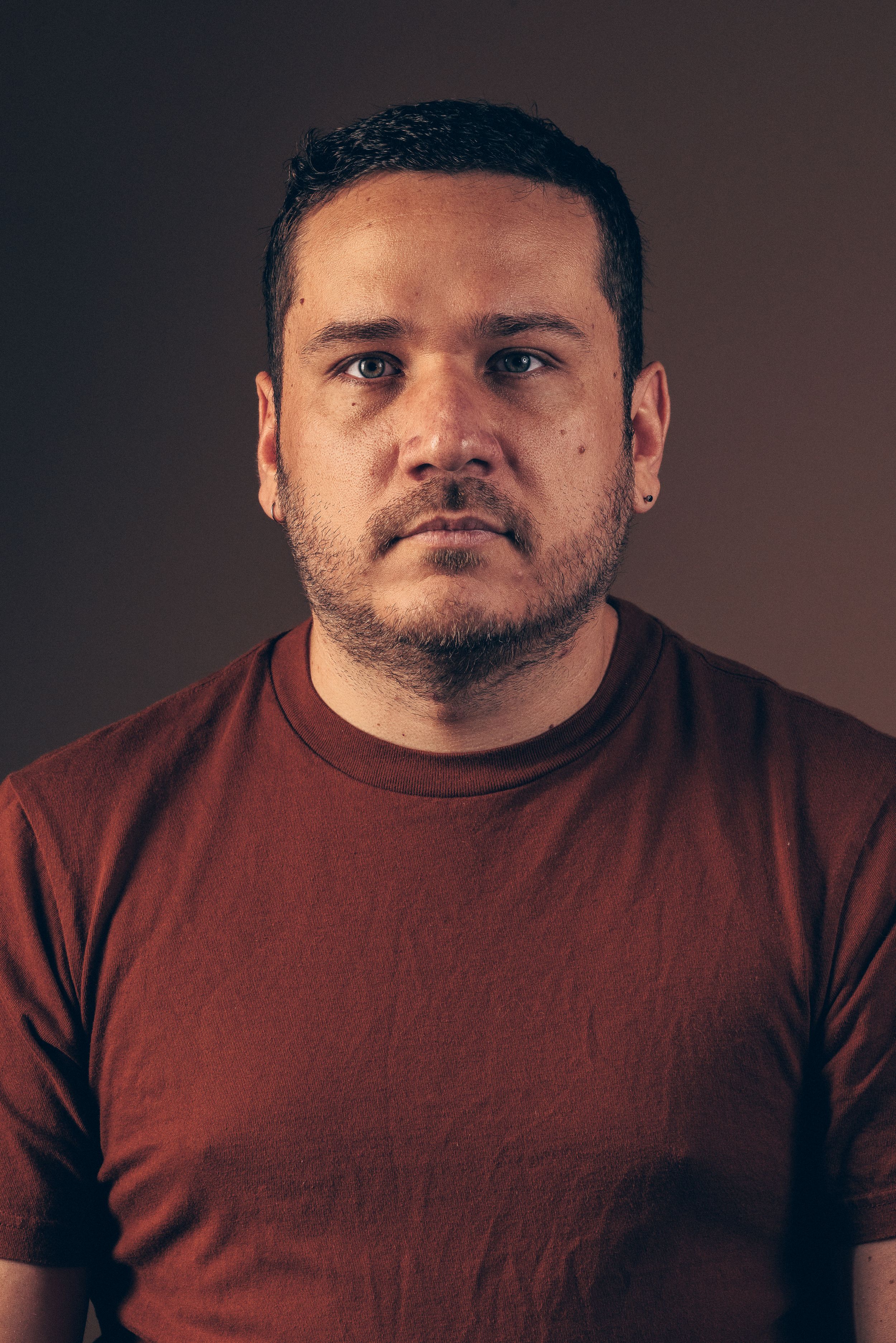 Portrait series showing changing facial expressions in a burgundy shirt against dark background.