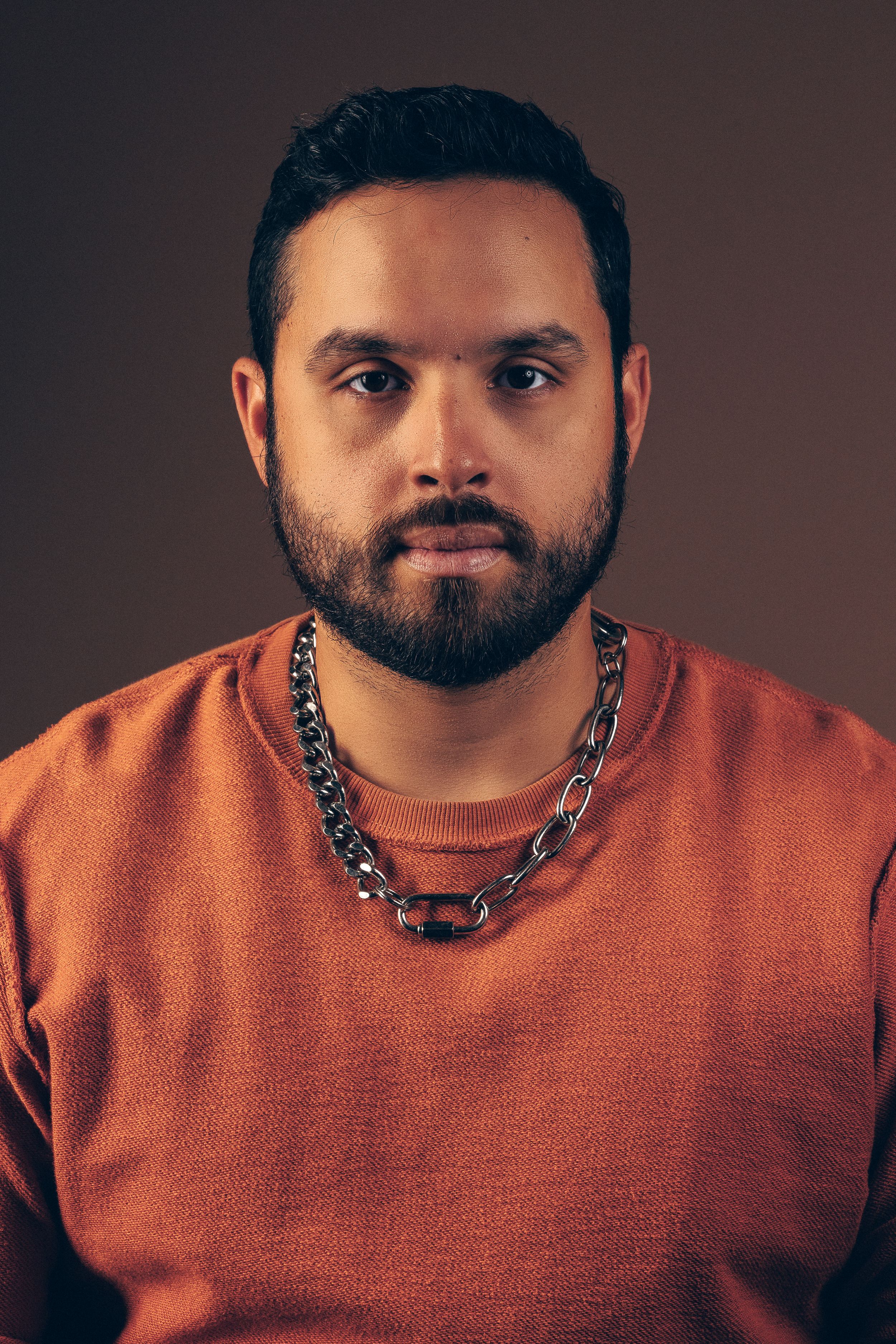 Portrait series showing person in orange sweater with metallic chain necklace against dark background.