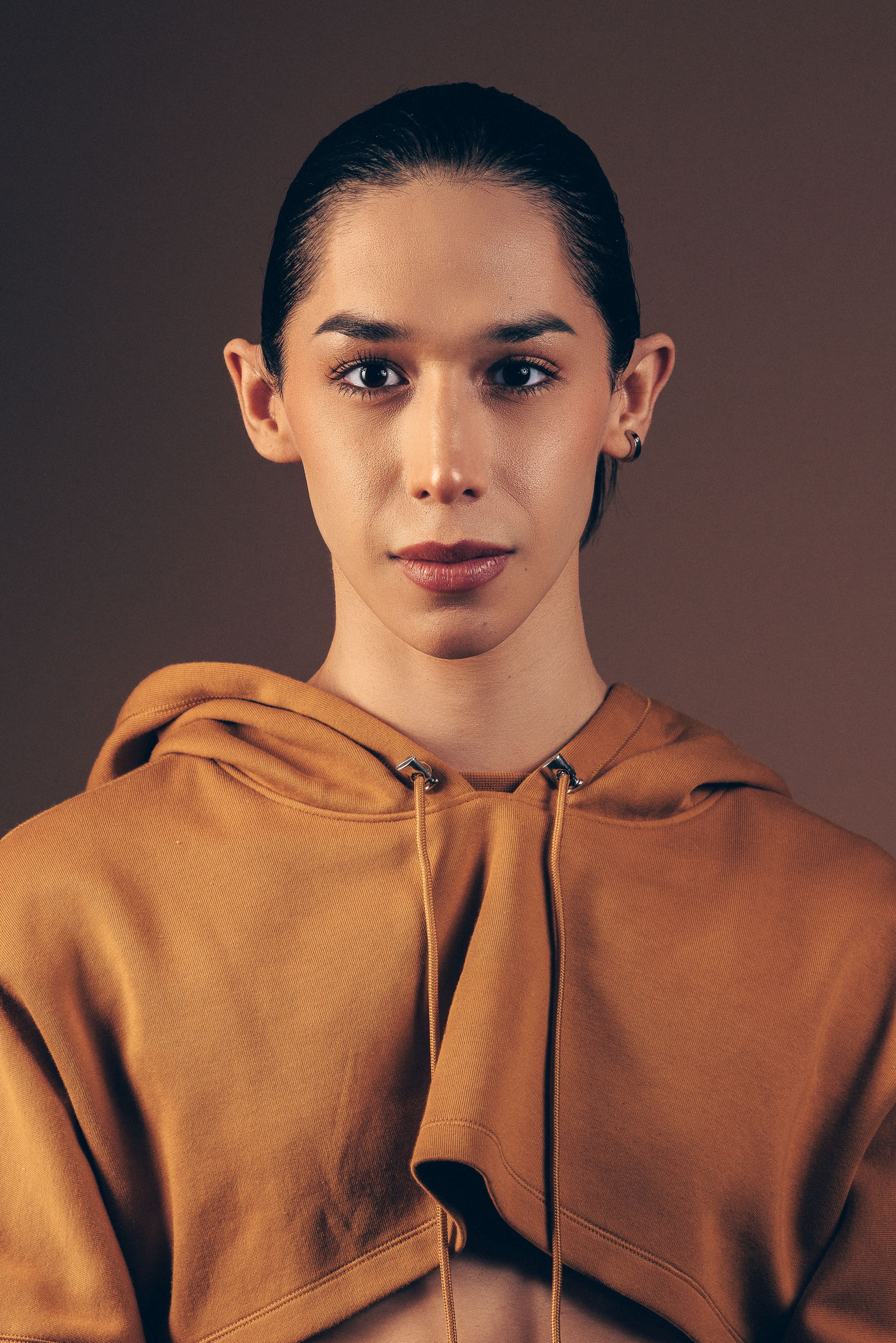 Artistic portrait sequence showing person in burnt orange hoodie against moody dark backdrop.