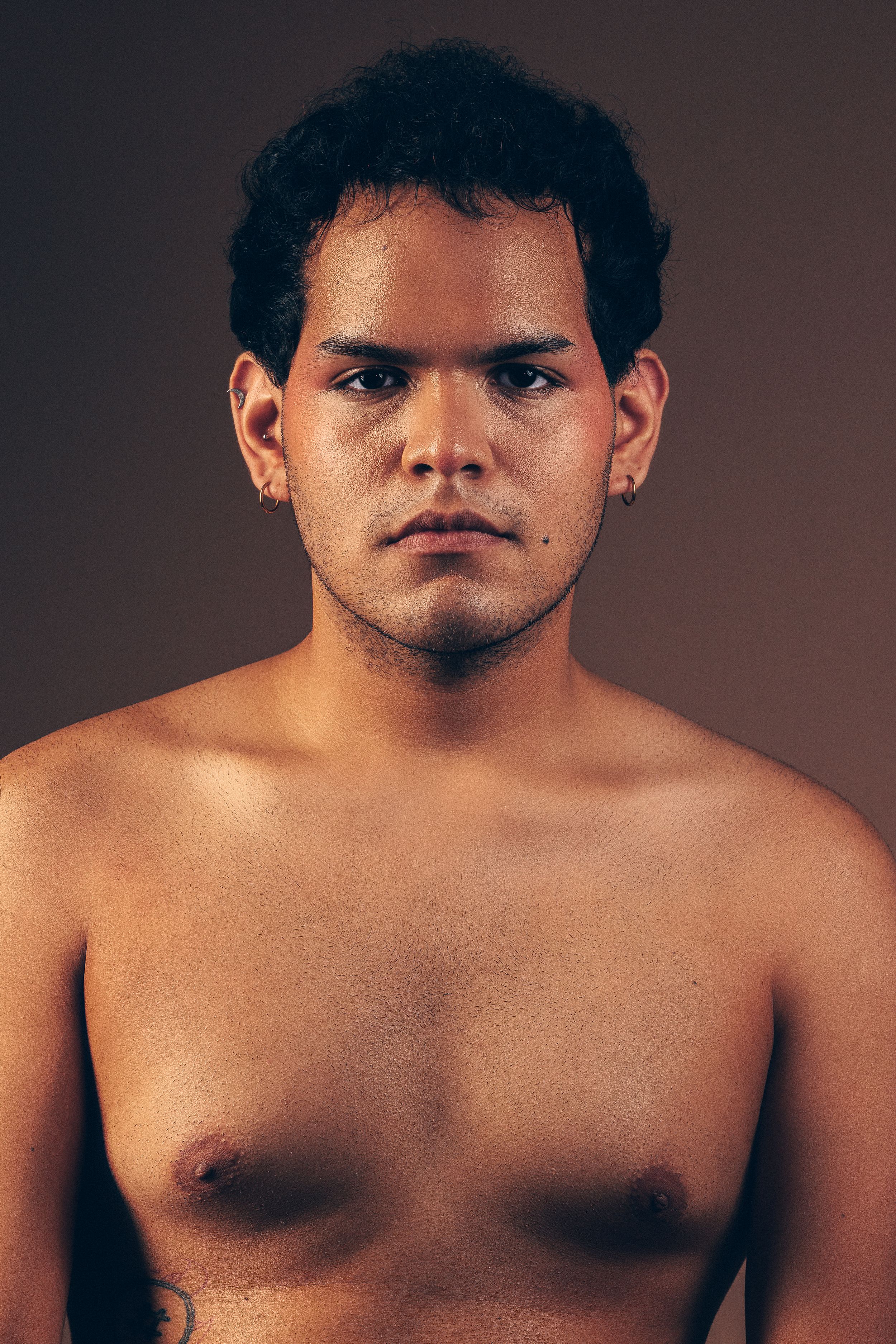 Artistic shirtless portrait series against dark brown studio background.