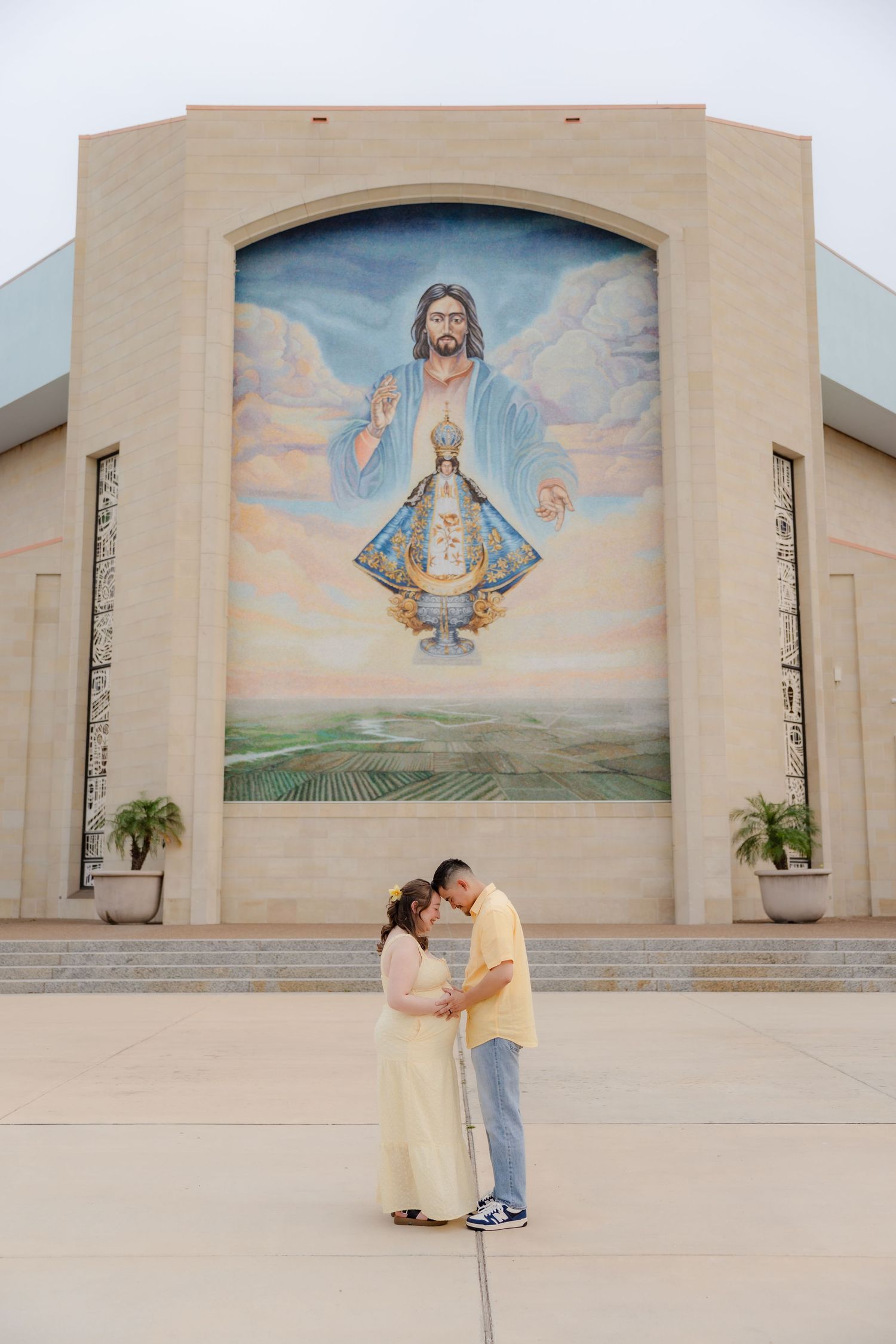 Proud PhD graduate in doctoral regalia wearing DACA and First Generation sashes outside a church. San Juan, Tx. Photoshoot.