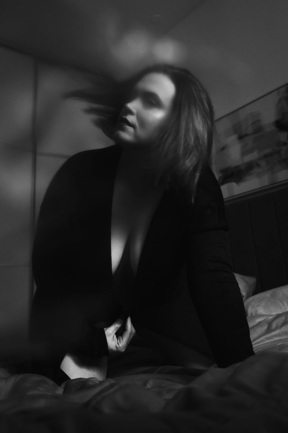 Moody crni i bijeli boudoir portret u slabom svjetlu s dramatičnim sjenama