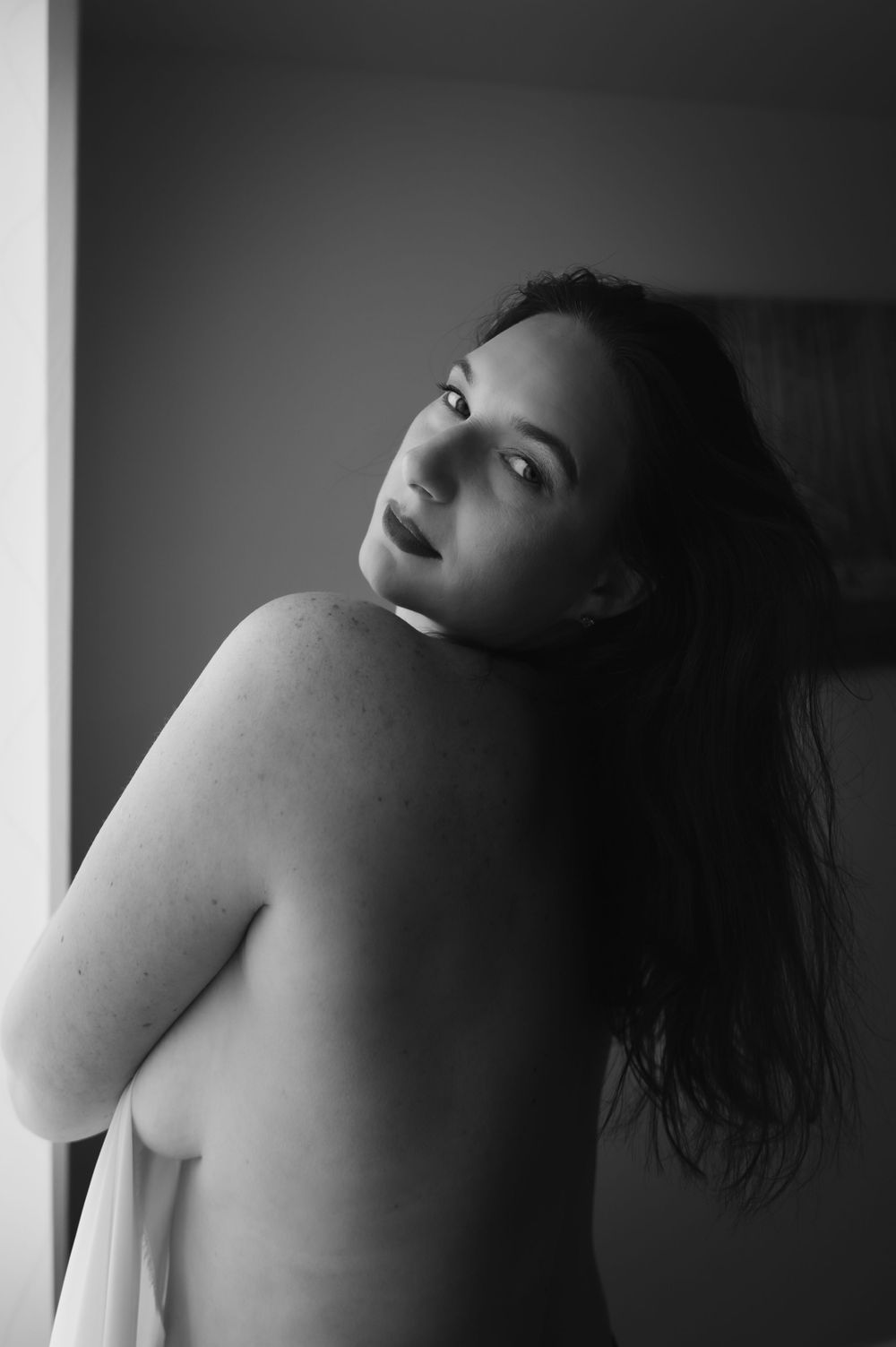 Dramatic black and white portrait with soft window lighting.