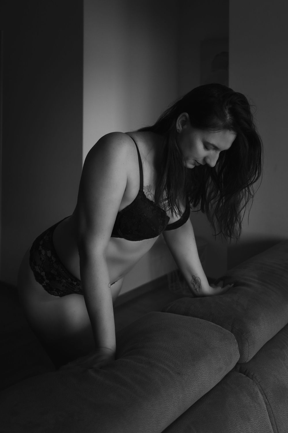 Intimate black and white photograph on a couch in dark lighting.