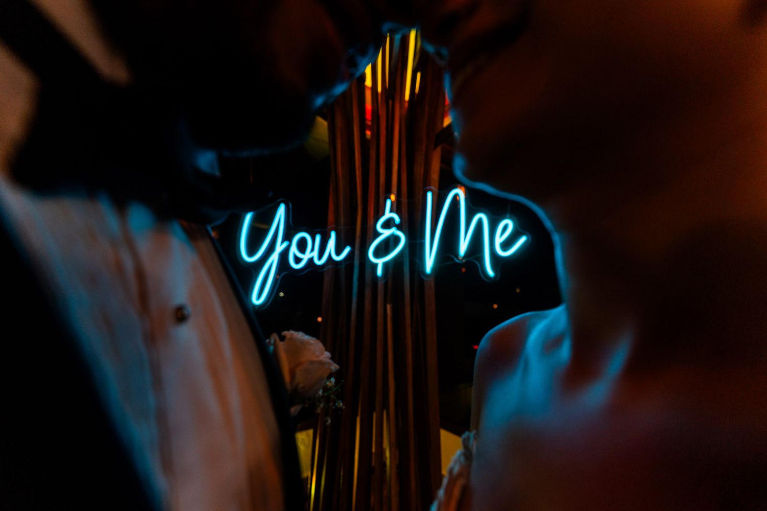 Blue neon sign reading 'You & Me' glowing against a dark background in romantic atmosphere.