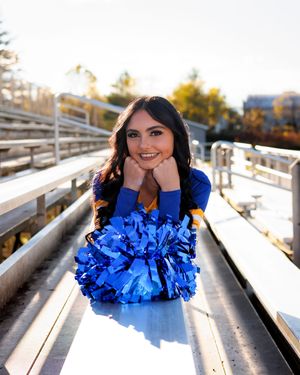 Cheerleader with blue and white pom poms poses on bleachers in a series of playful shots at sunset.