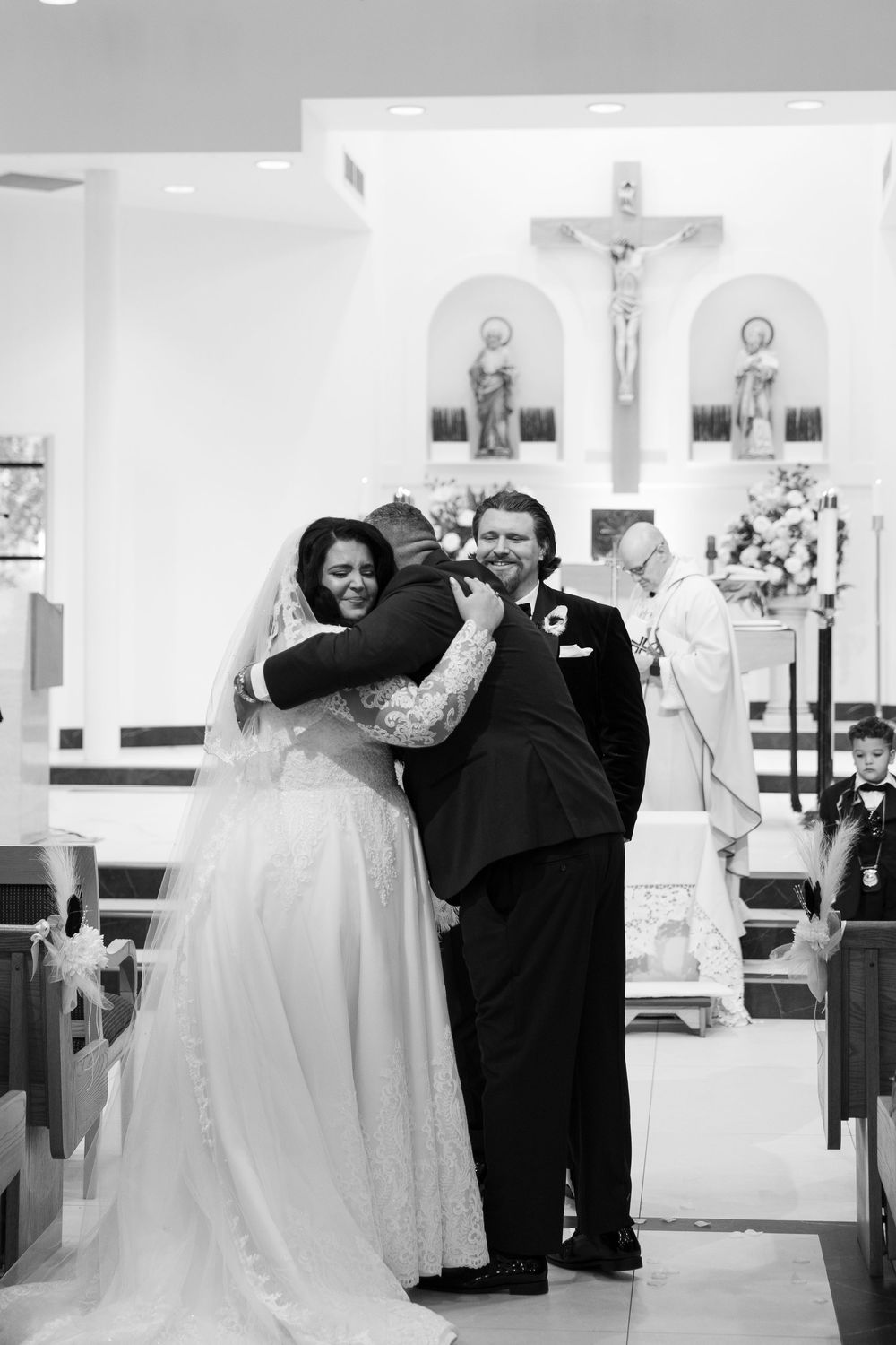 A black and white photograph of a joyful moment at a church wedding ceremony with religious iconography visible.