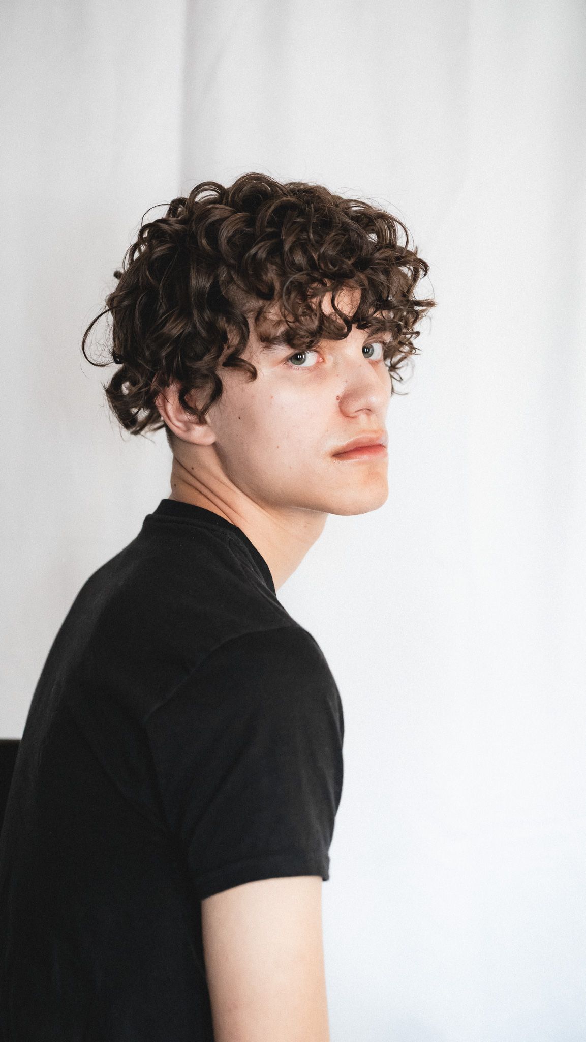 Side profile portrait against white background showing curly hair texture.