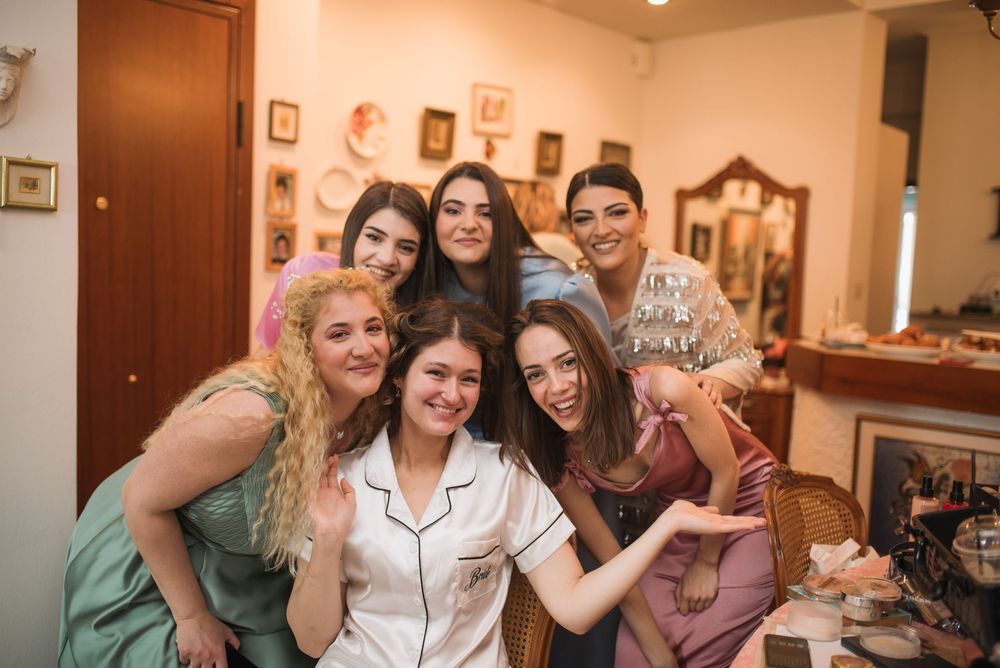 Group of bridesmaids in casual attire sharing a joyful moment during wedding preparations.