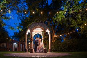 A nighttime wedding portrait under string lights and an illuminated stone archway at Casas de Suenos, in Albuquerque, New Mexico.