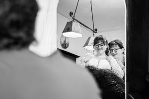A black and white film strip sequence showing movement under hanging pendant lamps in an interior space.
