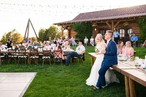 Guests socializing at a rustic wooden dining pavilion during an outdoor wedding reception.
