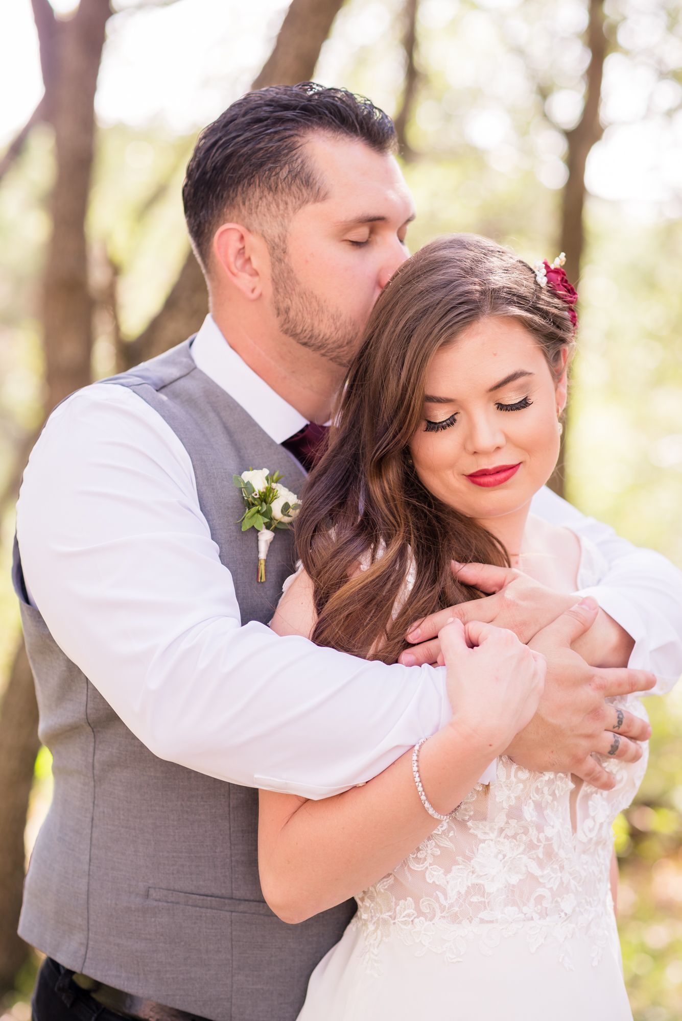 Romantic forest wedding portrait with soft natural lighting and floral accents.
