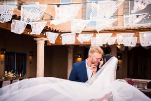 A romantic wedding moment captured under decorative papel picado banners at a southwestern style venue.