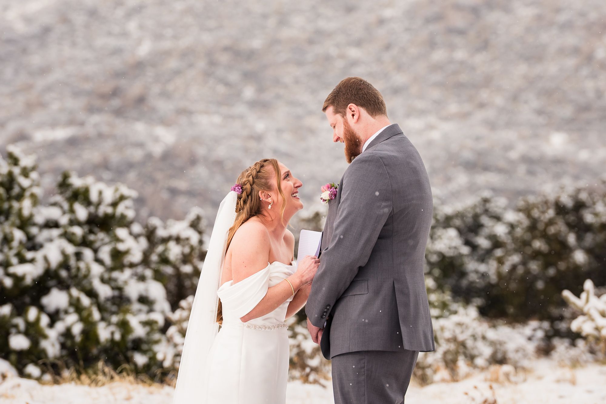 A couple in winter wedding attire shares intimate moments during their snowy mountain elopement.