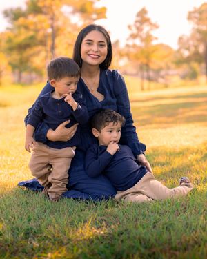 Family enjoying golden hour together on grassy hill during autumn sunset. In Houston, TX