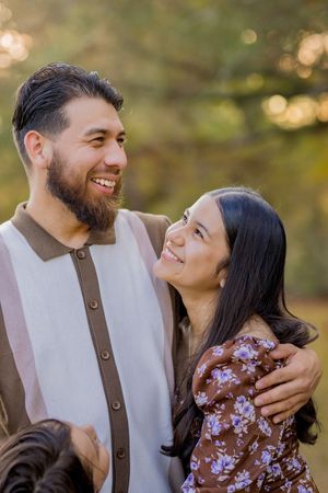 A couple shares a joyful moment together outdoors with warm sunset lighting and bokeh in the background.