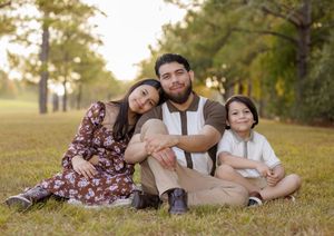 Family relaxing together on grass during golden hour sunset in a park setting.
