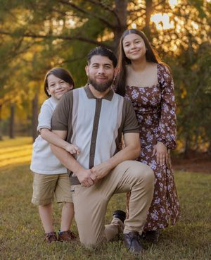 Family enjoying a warm sunset moment together in a grassy outdoor setting during golden hour.