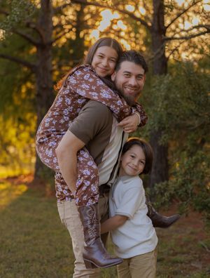 A playful family portrait showing group hugs and piggyback rides in a sunlit outdoor setting.