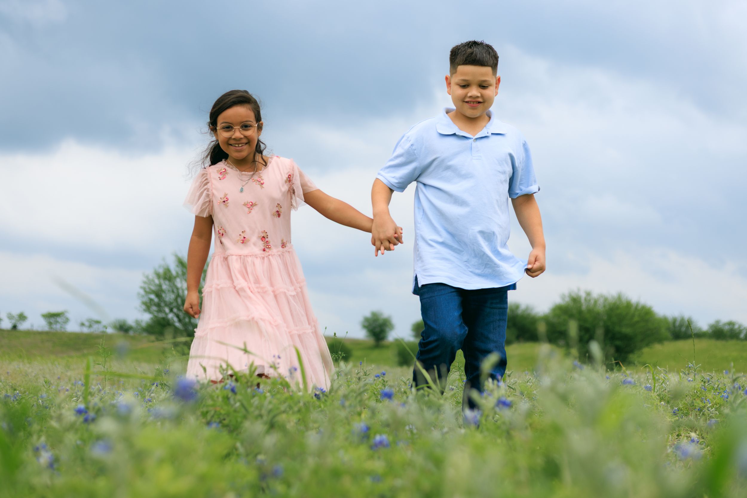Sibling skipping across the blue bonnet fields