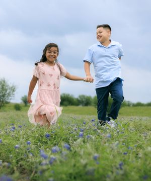 Sibling skipping across the blue bonnet fields