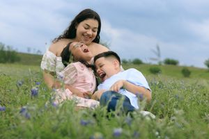Mommy tickling her little ones while hanging out in the blue bonnet field.