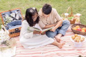 Siblings relaxing and reading during outdoor picnic