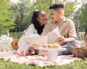 Brother and sister sharing a story during outdoor picnic time.