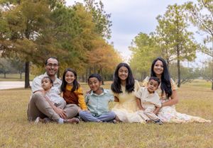 A group of people enjoying a casual autumn picnic on grass with golden fall foliage in the background.