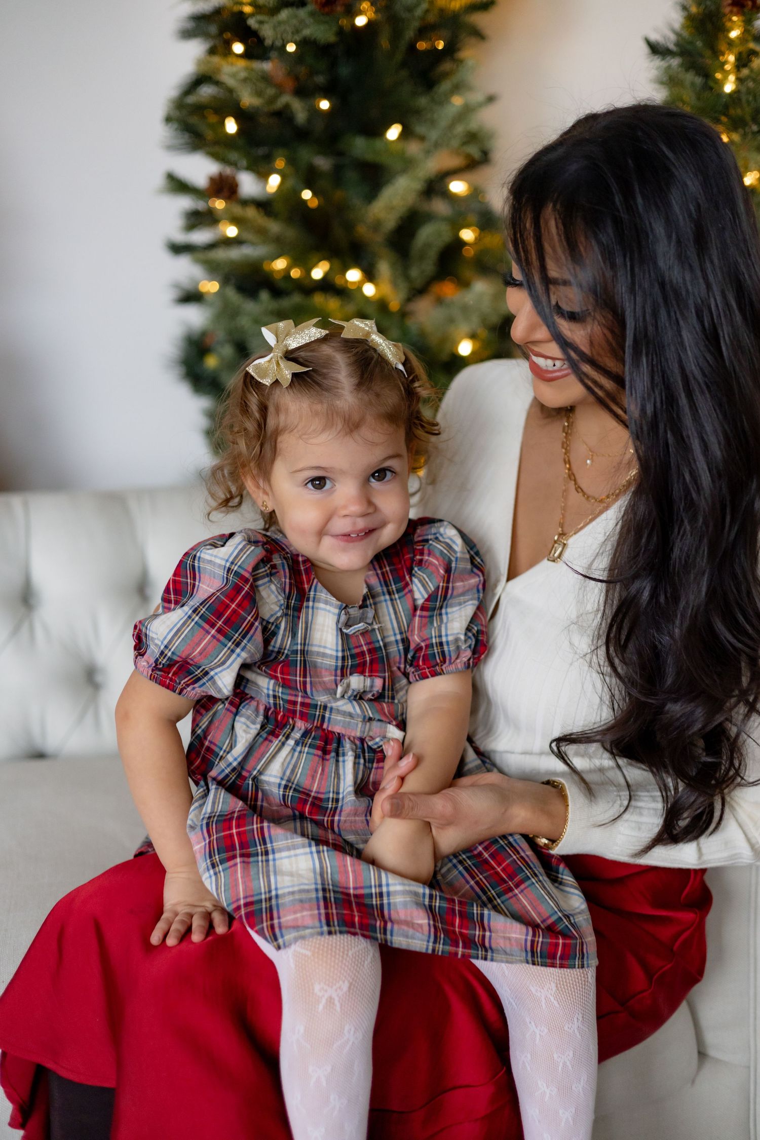 A festive Christmas portrait session featuring plaid dresses and a decorated tree in the background.