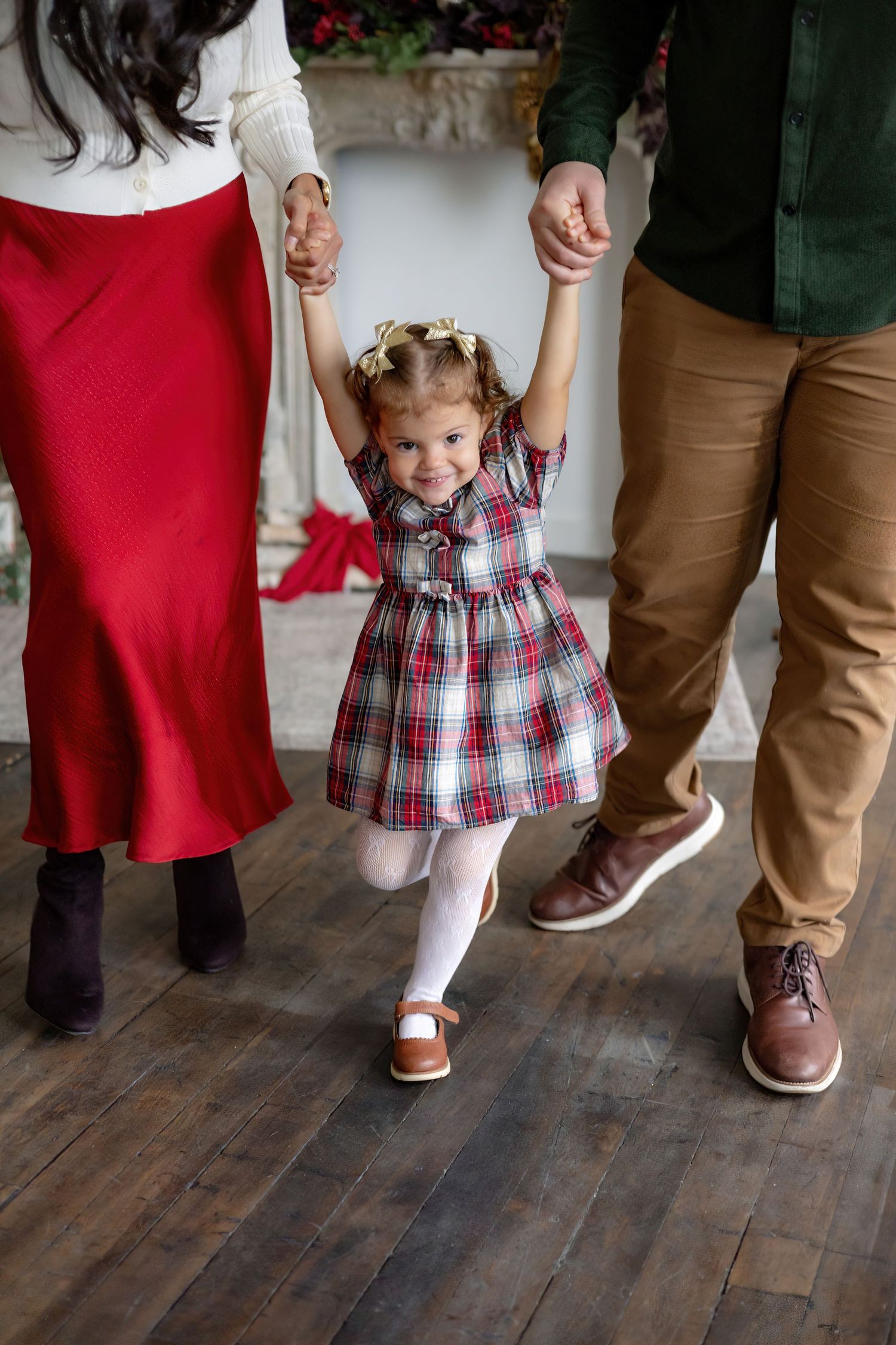 Close-up shots of feet showing a small plaid dress and brown leather shoes on wooden flooring.