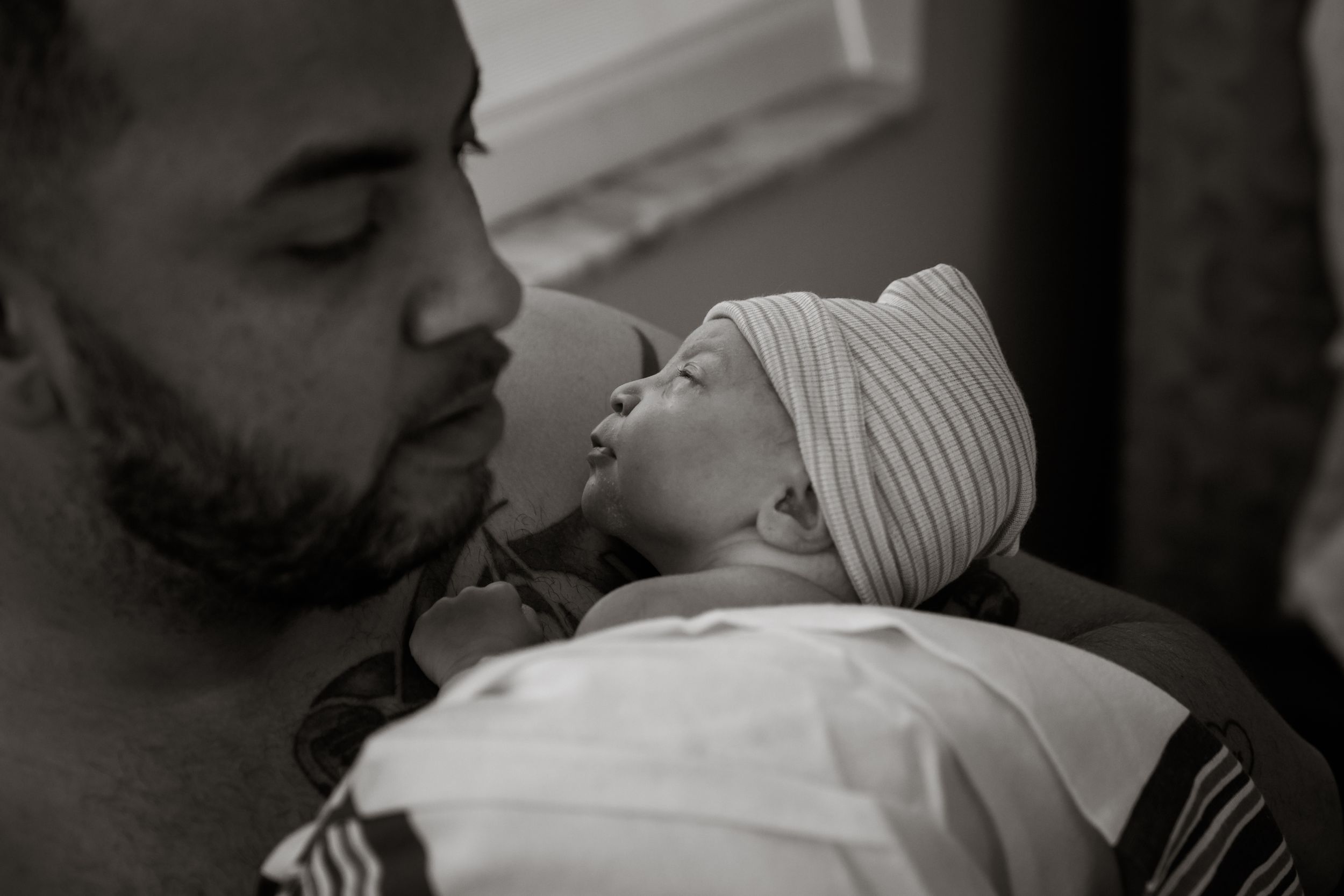Black and white portrait of peaceful Palm Beach newborn wearing striped hat.