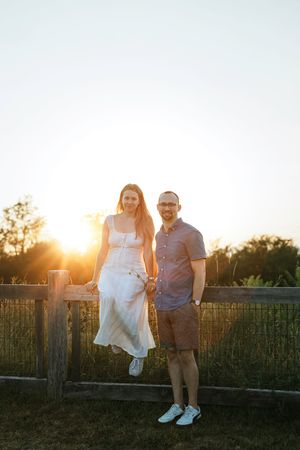 A couple shares a romantic moment at sunset on a rustic wooden bridge surrounded by golden light and natural scenery.
