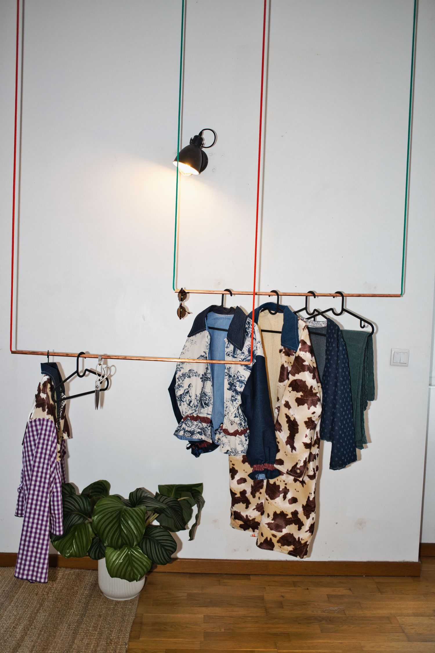 Photographie corporate à Bordeaux : détail d'atelier créatif, portant en cuivre et vêtements. Shooting branding pour marque de mode.