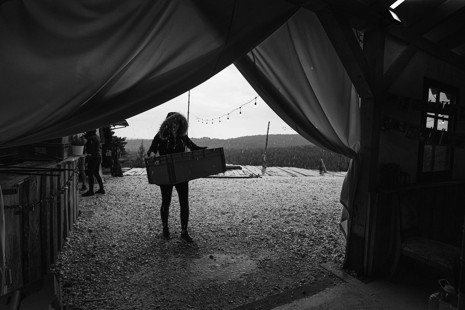 View through tent opening showing silhouette against rural landscape at dusk.