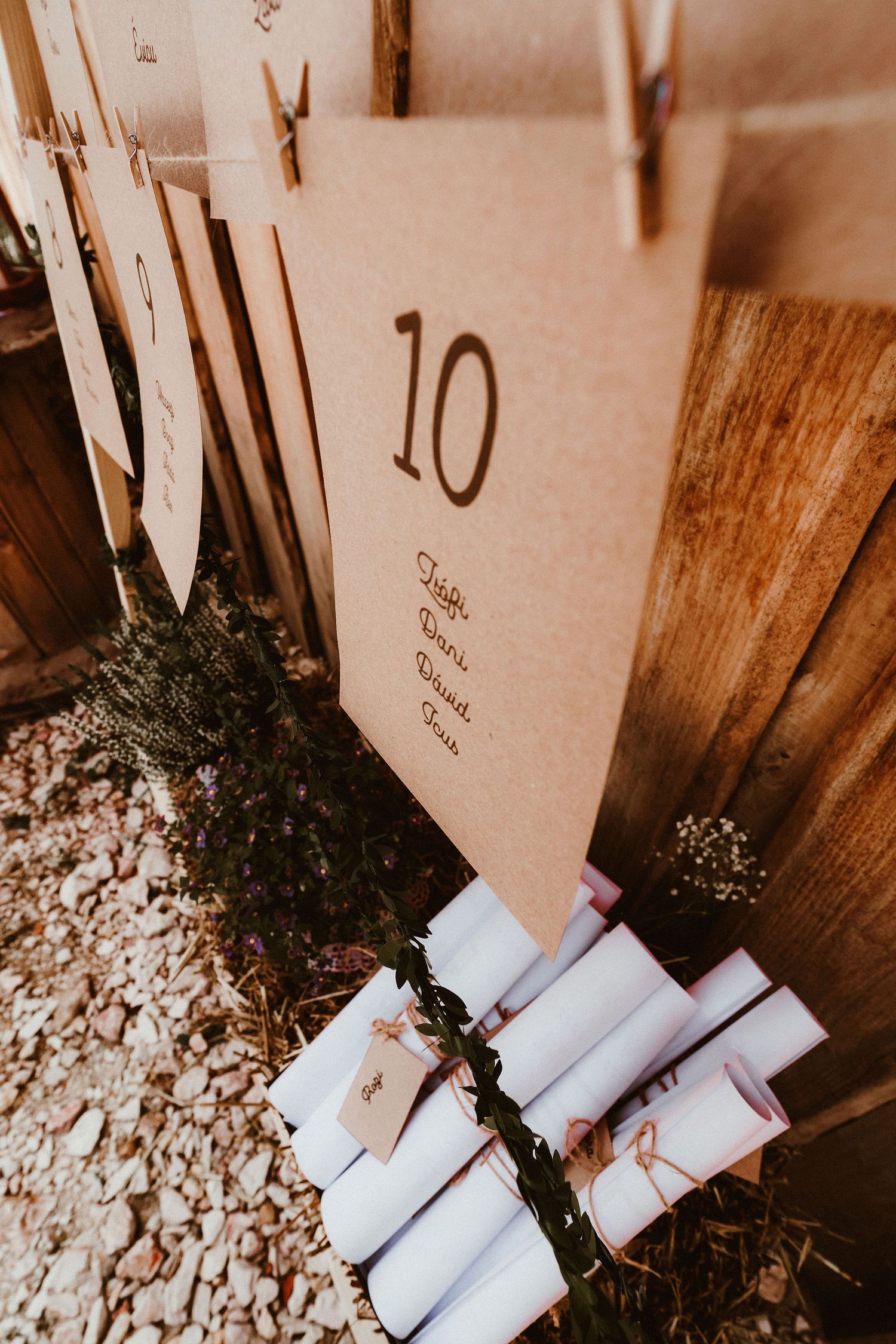 Wedding table number cards and scrolls arranged against wooden backdrop.