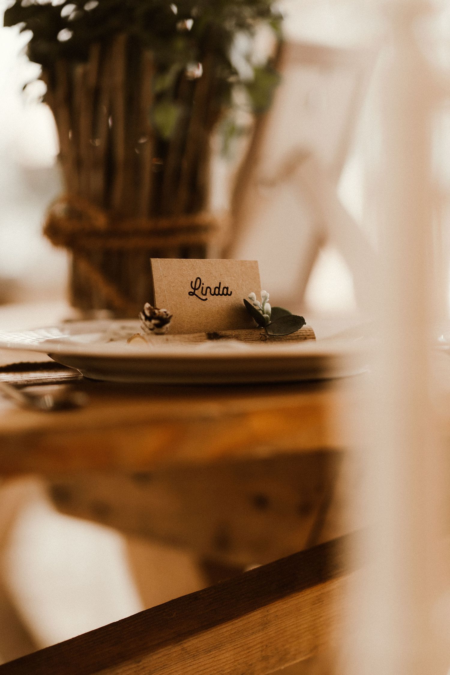 Place setting with name card and floral arrangement on wooden table.