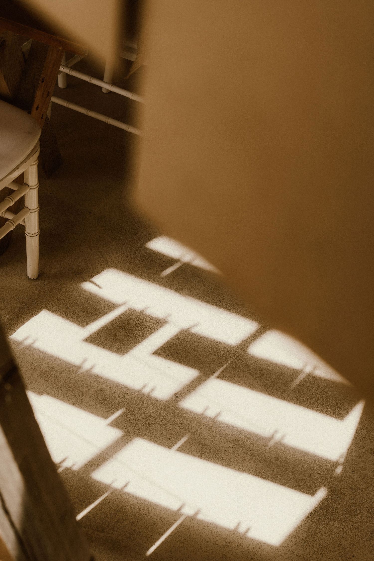 Geometric window light patterns casting shadows on wooden floor.